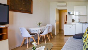 Un espace de vie compact comprenant un coin repas, une kitchenette et un téléviseur fixé au mur.