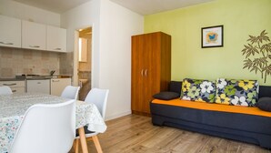 Ett kompakt bostadsutrymme med en matplats, ett litet kök och en soffa med blommiga kuddar.