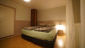 Ein Schlafzimmer mit einem Bett, einer Stehlampe und einem Backsteinsschornstein.