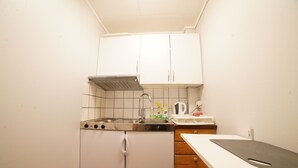 Eine kleine Küche mit weißen Schränken, einer Edelstahl-Spüle und einer Arbeitsplatte mit Schneidebrett.