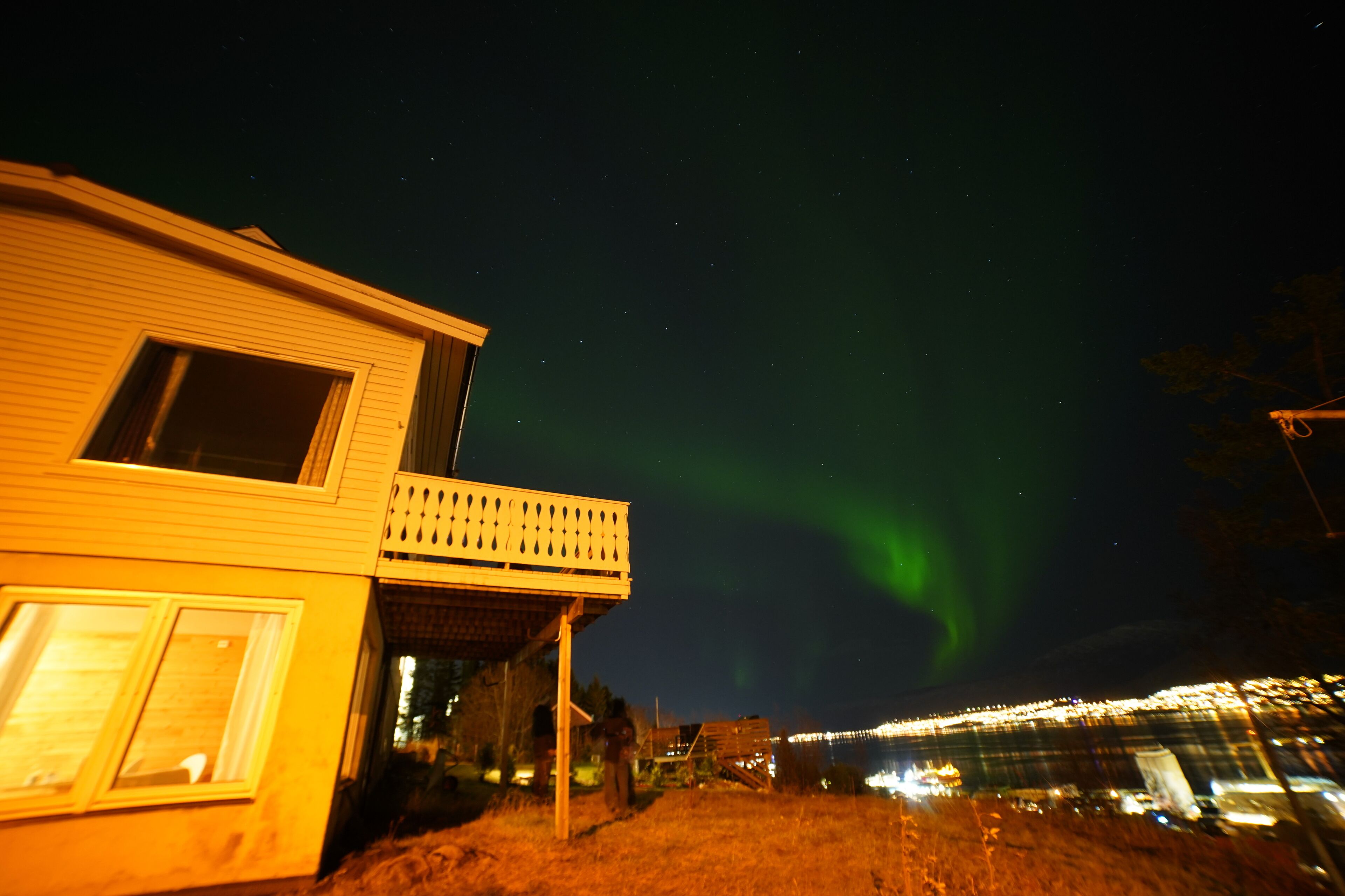 Ein Haus mit Balkon und Blick auf eine Stadtlandschaft sowie das Nordlicht.