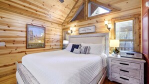 Un dormitorio de cabaña de madera con cama, mesitas de noche y cómoda.