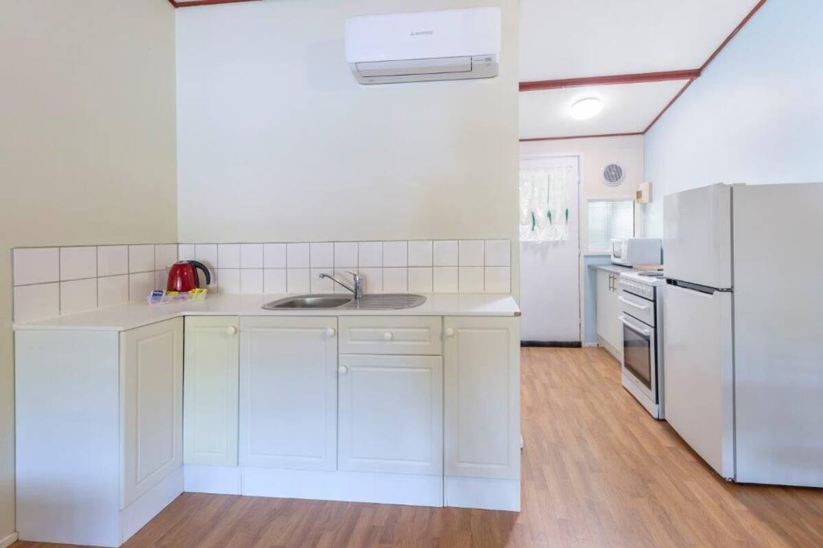 A compact kitchen with white cabinetry, a sink, a microwave, and a refrigerator.