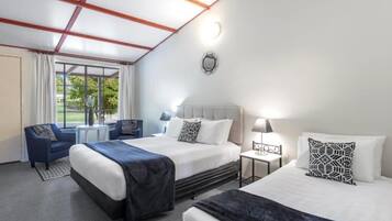 Habitación de hotel con dos camas, un escritorio, una silla y una ventana con cortinas.