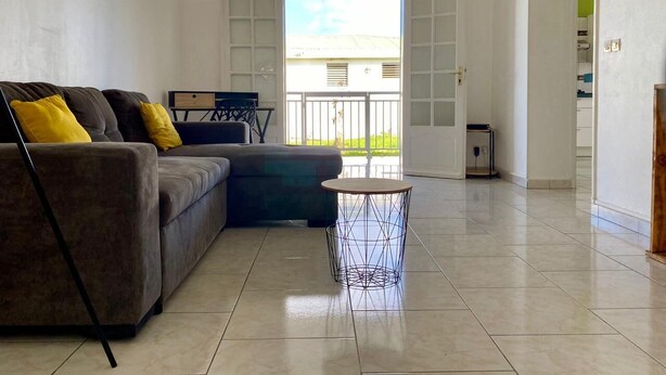 A living room with a sofa, a coffee table, and a view of the outside through a large window. - ★ Sopraia Nature ★ New ✯ Countryside ✯ Calm (Les Abymes)