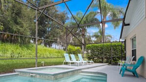 A swimming pool with clear water, surrounded by a covered patio area with chairs. - PROMO 5BR Villa with Pool/Spa, Near Disney - by Blue Sky Villas (Kissimmee)