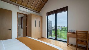 Ein Schlafzimmer mit einem großen Bett, einem Holzschrank und Blick ins Freie durch eine Schiebetür.