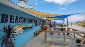 Restaurante com tema praiano, mesas ao ar livre, um mural e vista para a praia.
