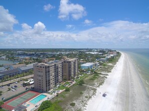 Un hôtel situé sur la côte, doté d’un grand bâtiment, d’une piscine et d’une plage.