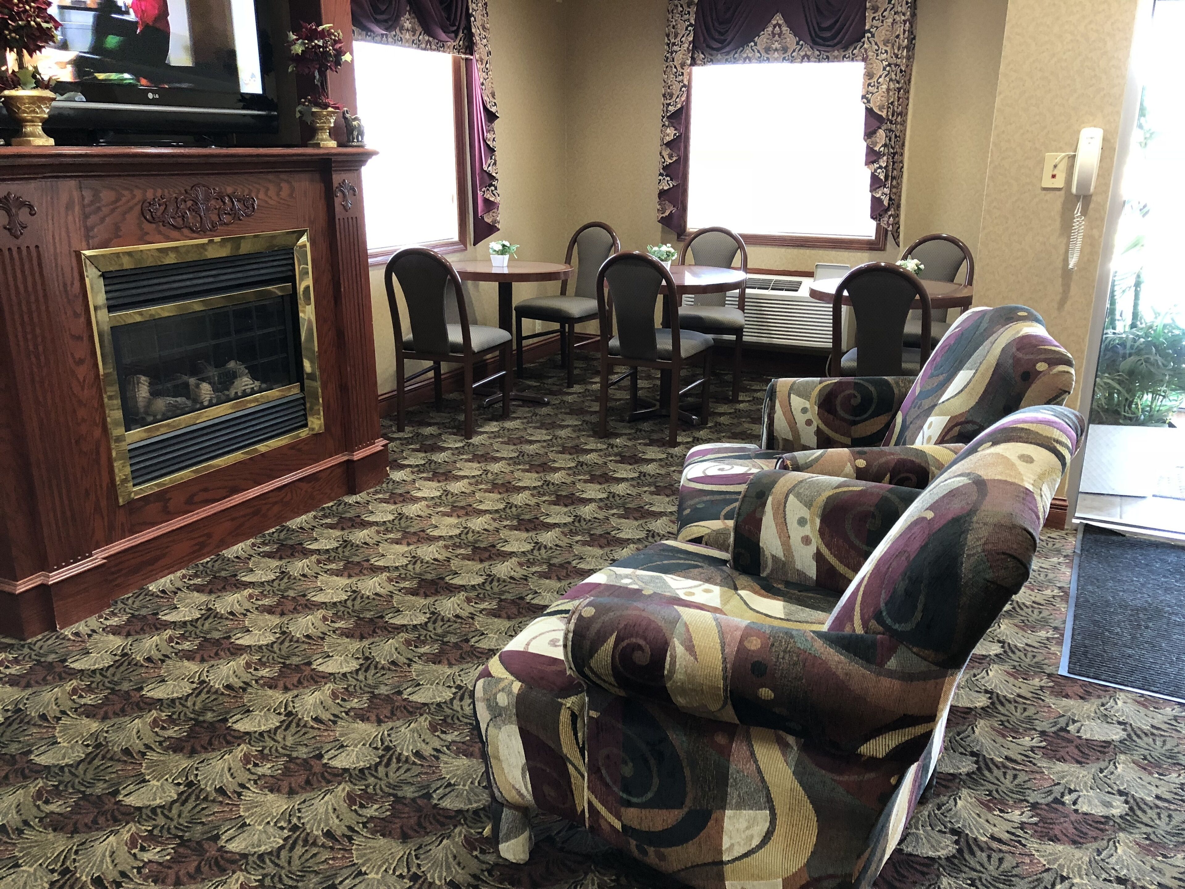 A living room with a fireplace, patterned carpet, and a sofa with a colorful design.