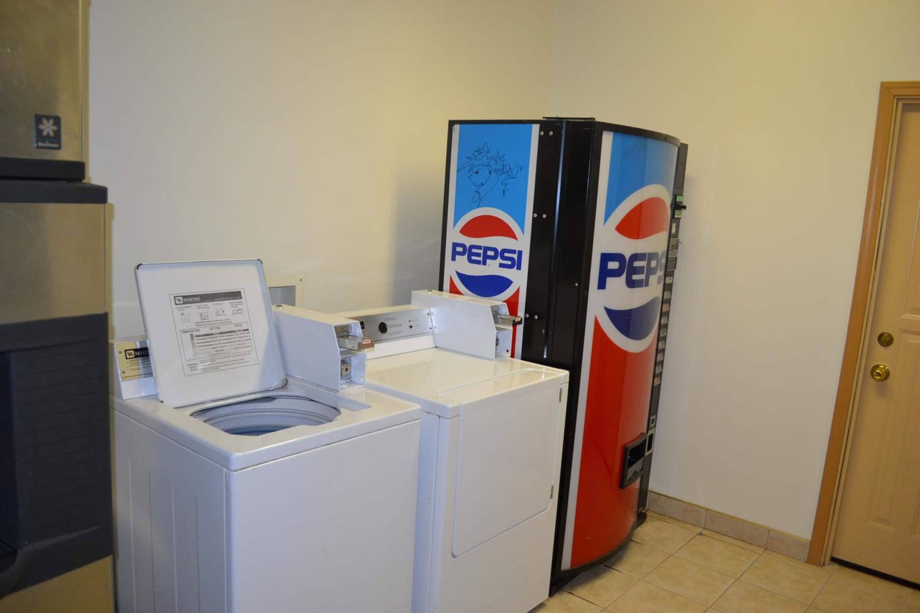 Un área de lavandería con lavadora y refrigerador con la marca Pepsi.