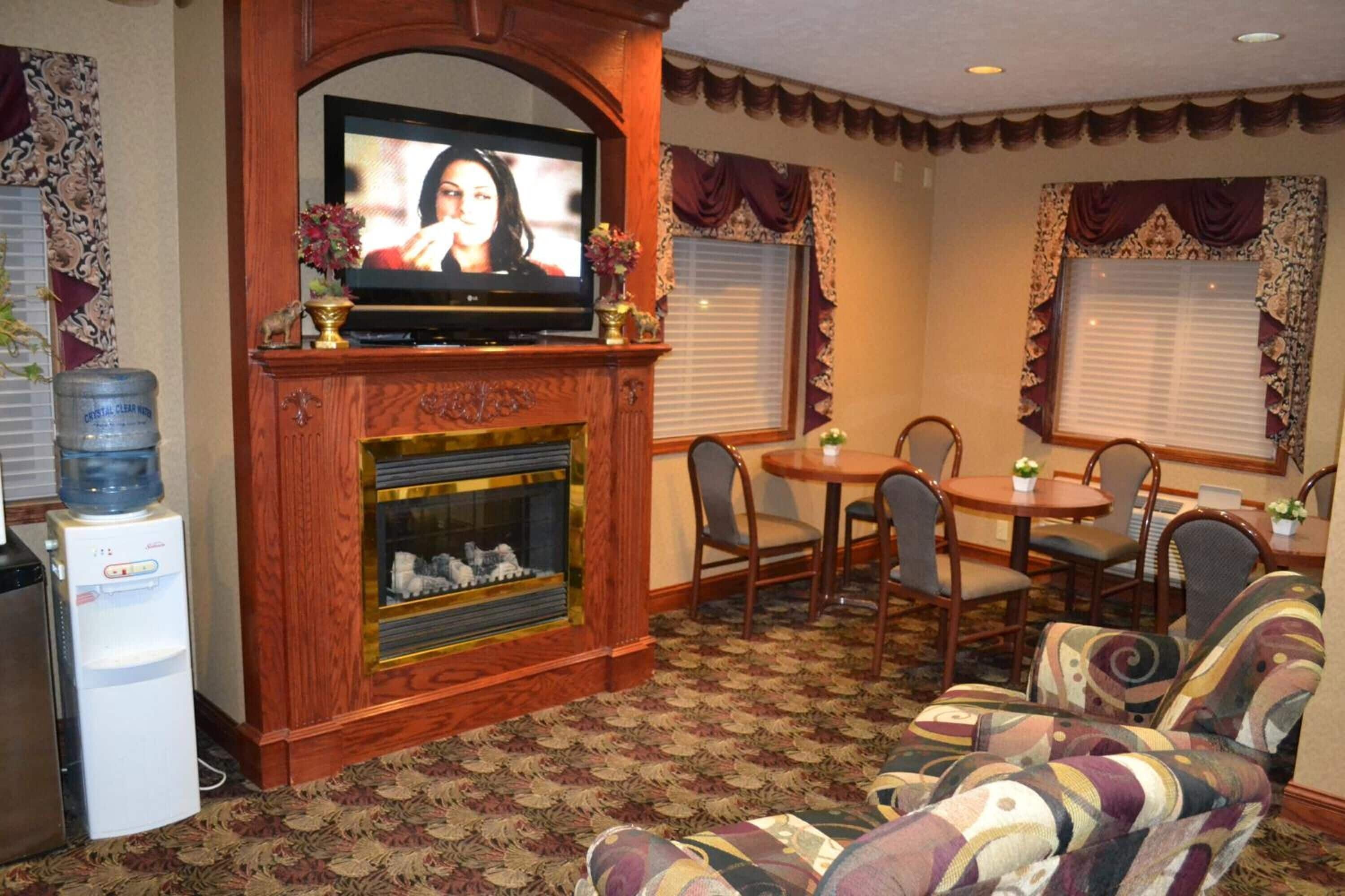 A living room with a fireplace, a television, a water dispenser, and a dining area with chairs and a table.