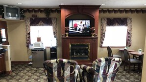 Uma sala de estar com lareira, dois poltronas, uma televisão e um micro-ondas.