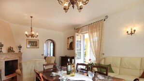 Un coin repas avec une table en bois dressée pour deux personnes, une cheminée et un canapé.