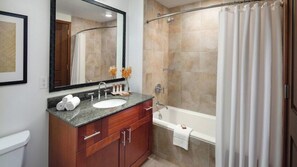 Un baño con lavamanos, espejo, tocador, ducha y bañera.