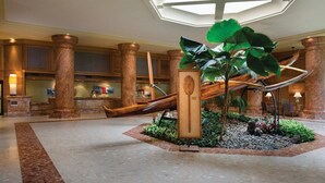 Un vestíbulo con una planta central, un tobogán y una mesa de recepción.