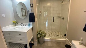 Een moderne badkamer met een witte wastafel, spiegel en douche.