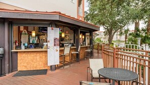 Un área de bar al aire libre con asientos, un tablero de menú y vistas de los edificios circundantes.