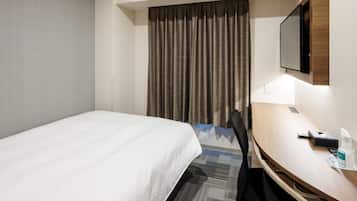 A hotel room with a bed, a desk, a chair, a television, and a curtain.
