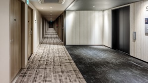 A hotel corridor with carpeted flooring, wooden doors, and a modern elevator. - Smile Hotel Okayama (Okayama)