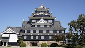 A traditional Japanese castle with multiple levels, white window frames, and a prominent golden roof ornament. - Smile Hotel Okayama (Okayama)