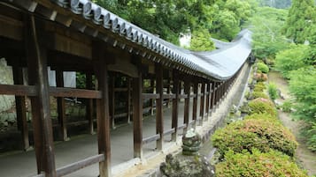 A traditional wooden structure with a curved roof, surrounded by lush greenery and stone pathways.