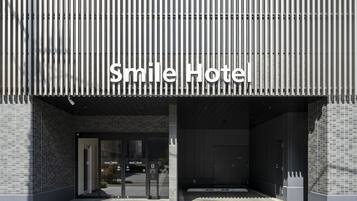 The exterior of the Smile Hotel with a modern facade, large glass entrance, and a prominent sign.