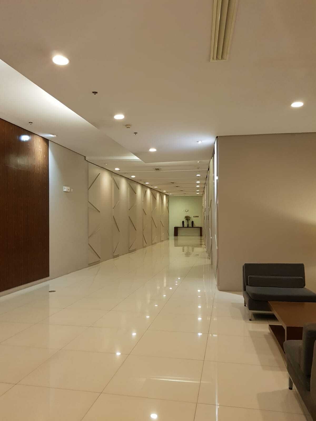 Un moderno vestíbulo de hotel con un largo pasillo, una recepción y una zona de estar.