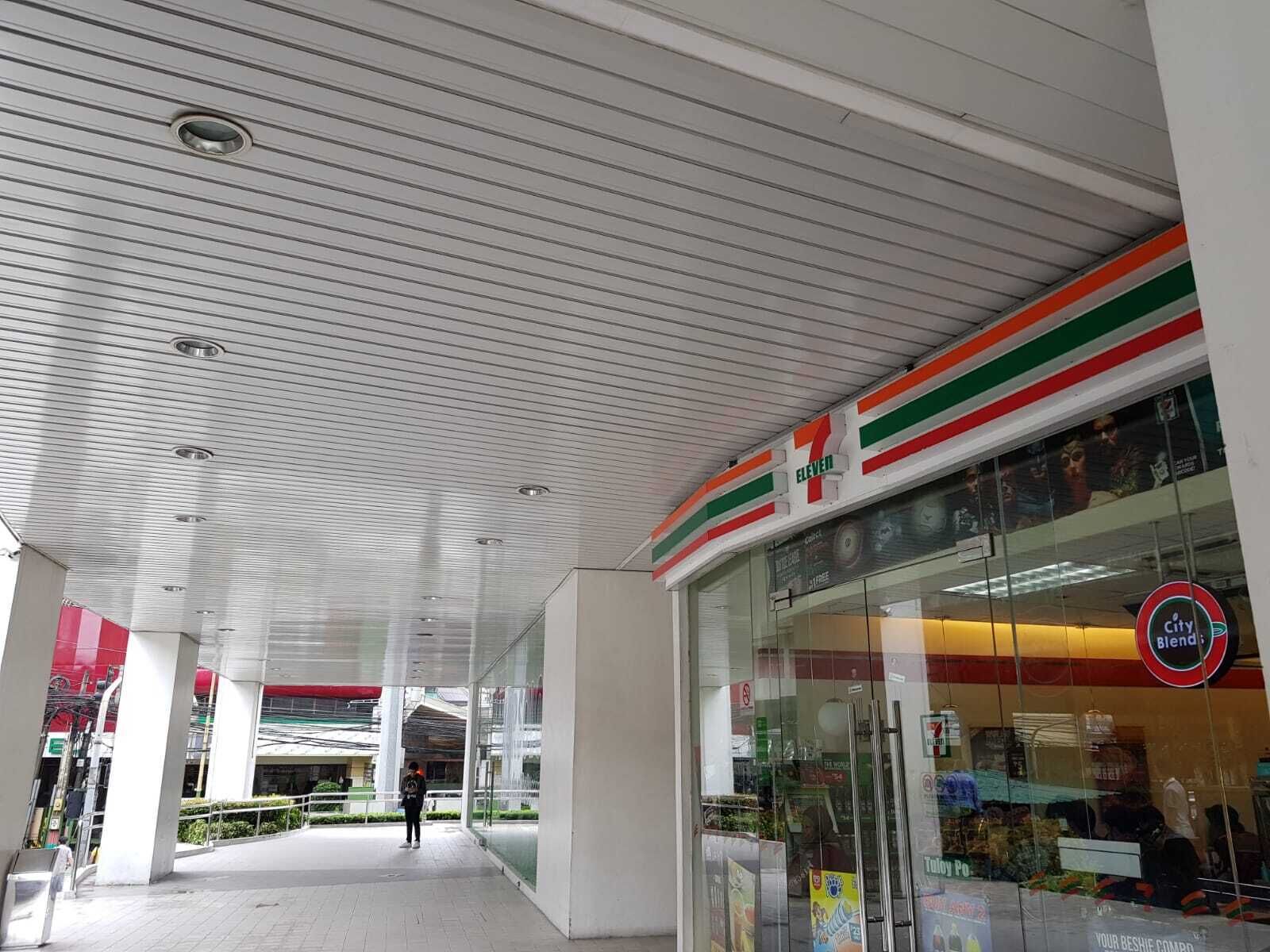 A 7-Eleven store with a modern design, including a glass facade and a metal ceiling with linear patterns.