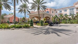 A hotel with a covered entrance, palm trees, and a paved driveway.