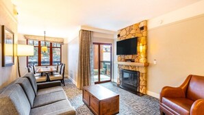 Una sala de estar con sofá, mesa de centro, chimenea, televisor y comedor con mesa y sillas.