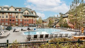 Un hotel con piscina, sillas de descanso y una terraza cubierta.