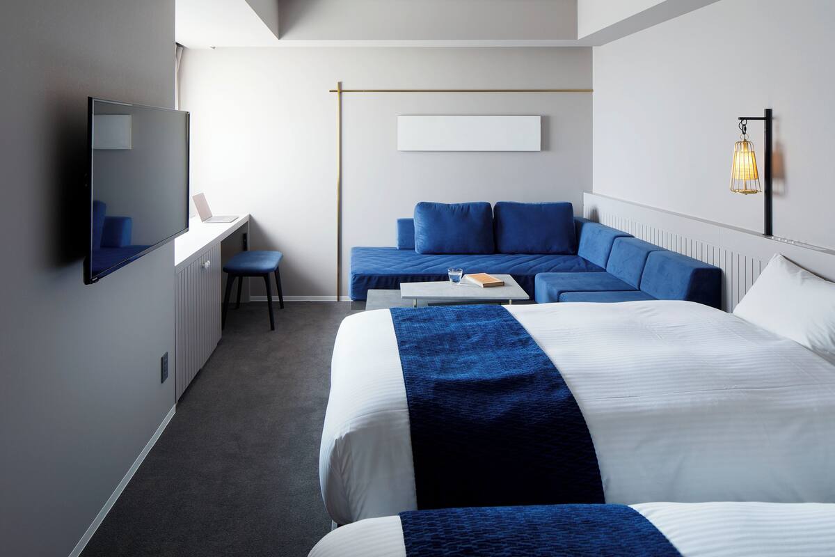 A modern hotel room with a large bed, a sofa, a desk, and a television.