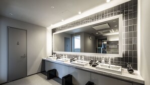 Een moderne badkamer met een grote spiegel, twee wastafels en een douchehoek.