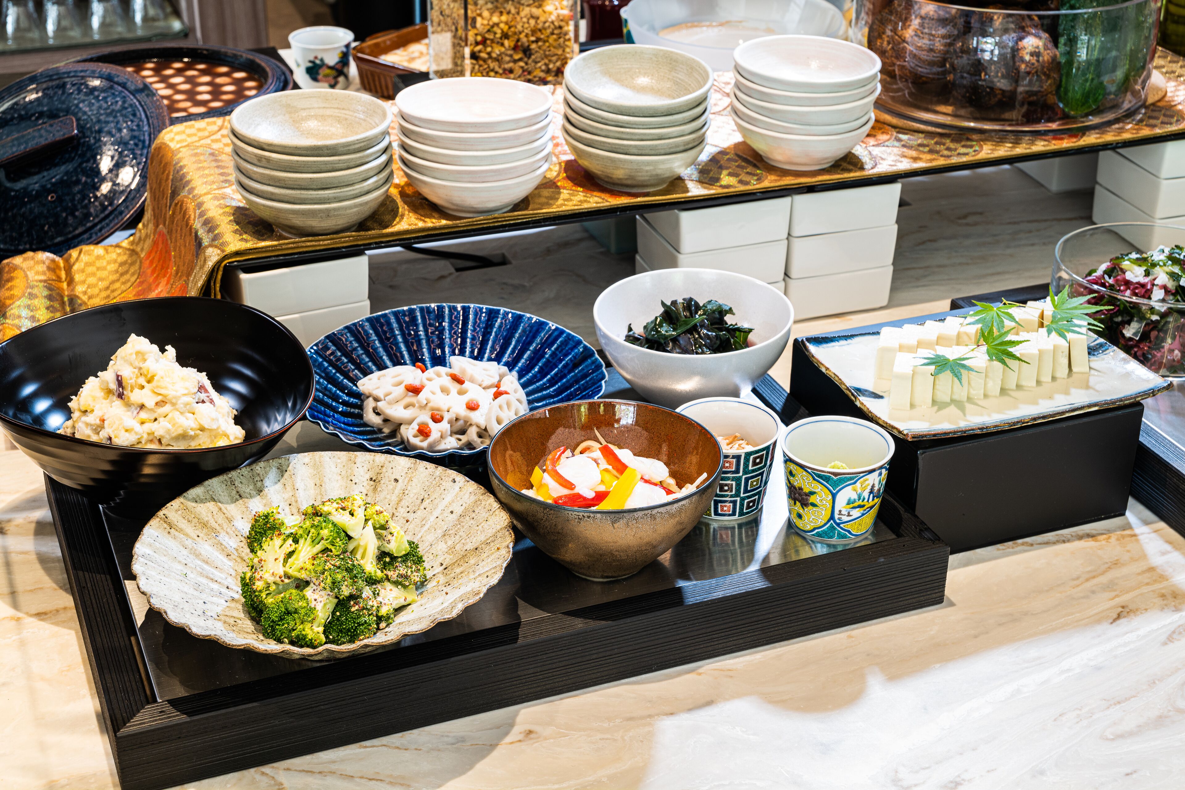 A buffet table with various dishes and bowls.