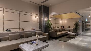 A modern lobby with a seating area, a reception desk, and a staircase.