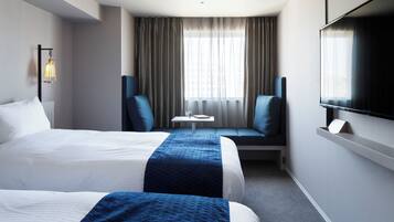 A hotel room with two beds, a TV, a small table, and a sofa.