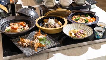 A variety of dishes on a table, including seafood, vegetables, and possibly meat, with bowls and plates arranged around a central heating element.