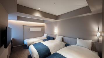 Une chambre d’hôtel avec deux lits, un téléviseur à écran plat et un luminaire fixé au mur.