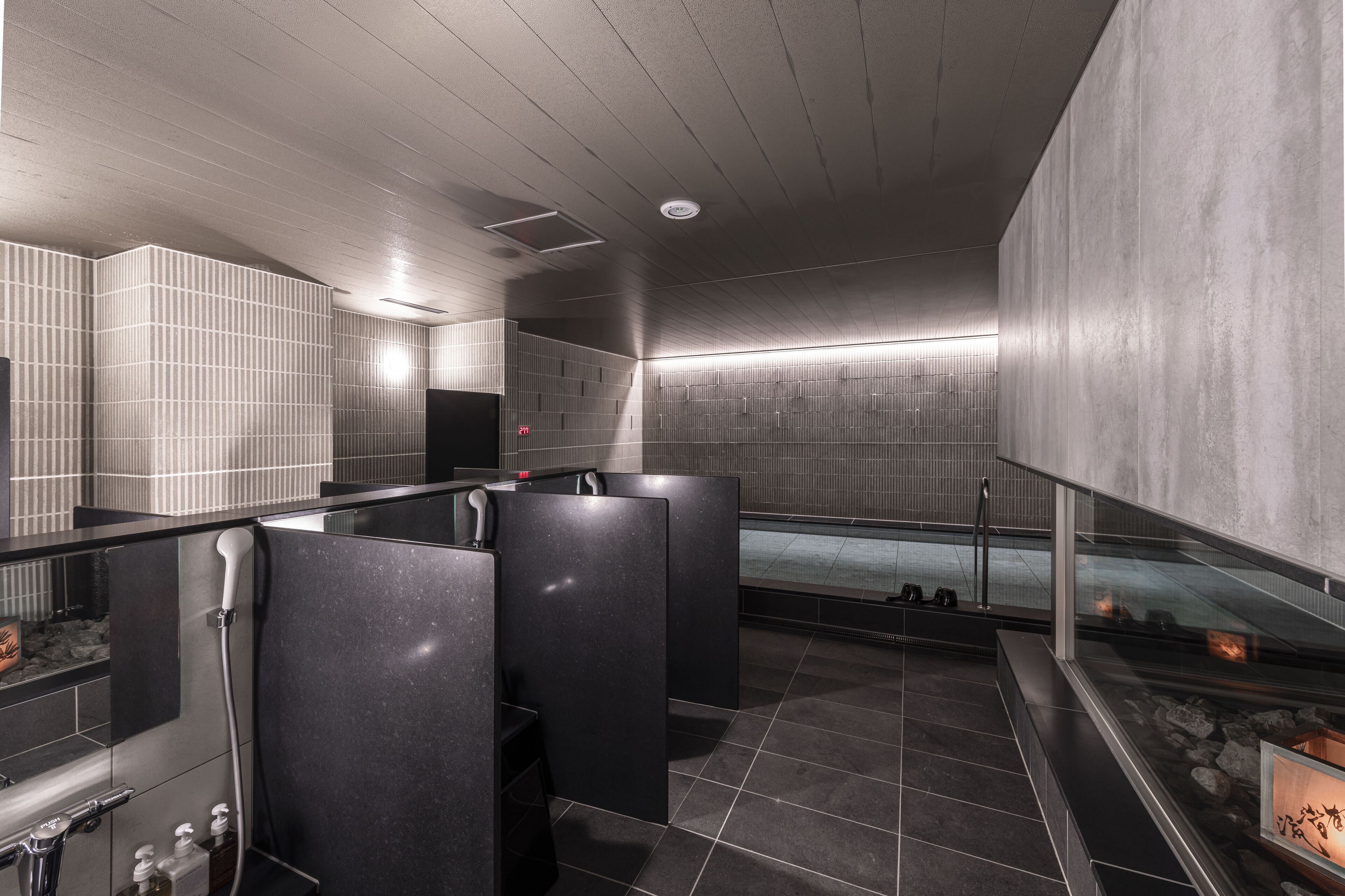 A modern bathroom with tiled walls, a shower area, and a glass partition.