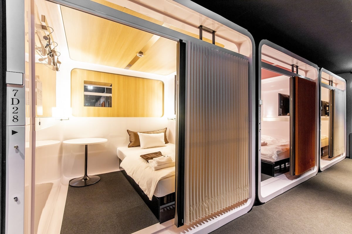 Una habitación de hotel moderna con cama, mesita de noche y una pequeña mesa redonda.