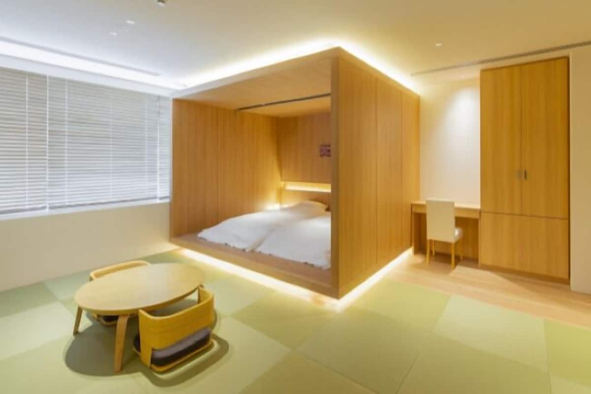 Un dormitorio moderno con cama empotrada, un escritorio y una zona de comedor.