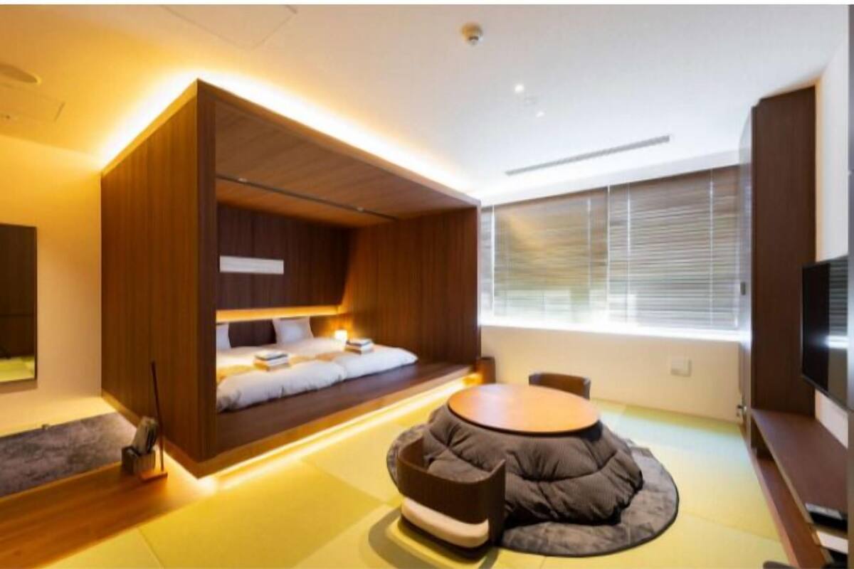 Una habitación moderna con una cama empotrada, una mesa de centro redonda y un televisor.