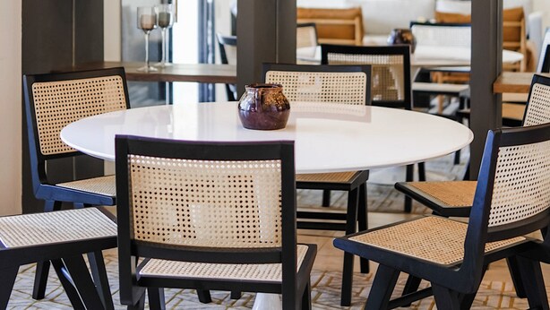 Un comedor con una mesa redonda, sillas negras y una lámpara colgante.