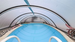 A transparent greenhouse structure with a pool inside.