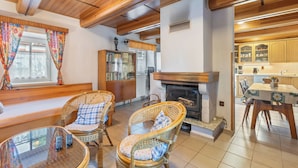 A cozy living room with wicker furniture, a fireplace, and a kitchen area visible through an open door.