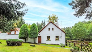 A white building with a red roof, surrounded by a well-maintained lawn and trees.