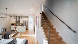 A modern interior with a wooden staircase, a dining area with a bench, and a kitchen with a central island. - Insta-worthy Views, Wine, Rooftop Firepit on Beach (Seattle)