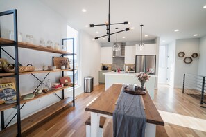 A modern kitchen with wooden shelves, a central island, and a hanging light fixture.