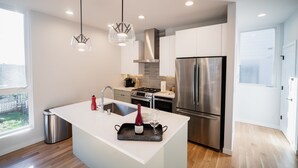 A modern kitchen with a central island, stainless steel appliances, and pendant lighting. - Insta-worthy Views, Wine, Rooftop Firepit on Beach (Seattle)